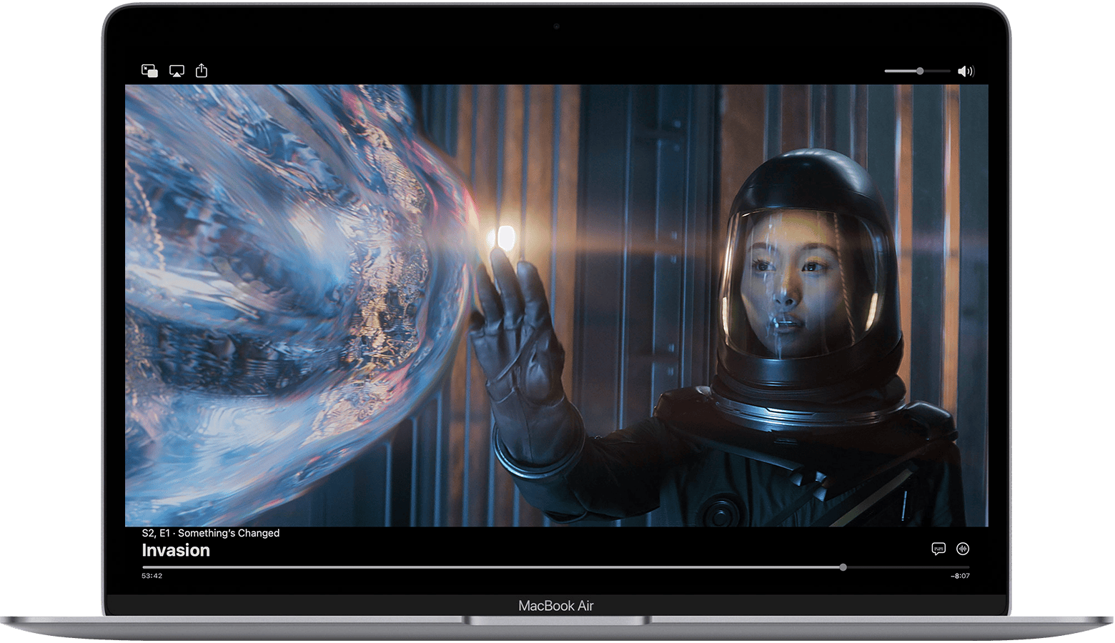 MacBook Air에서 Apple TV 앱이 일시 정지되어 있고 제어 항목이 표시되어 있습니다. 에피소드는 Invasion의 'Something’s Changed'입니다. 오른쪽 하단의 진행 막대 위에 자막 언어 버튼과 오디오 버튼이 있습니다.