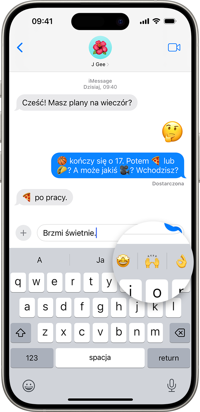 Ekran iPhone’a przedstawiający rozmowę w aplikacji Wiadomości z powiększoną predykcyjną ikoną emoji na górze klawiatury.